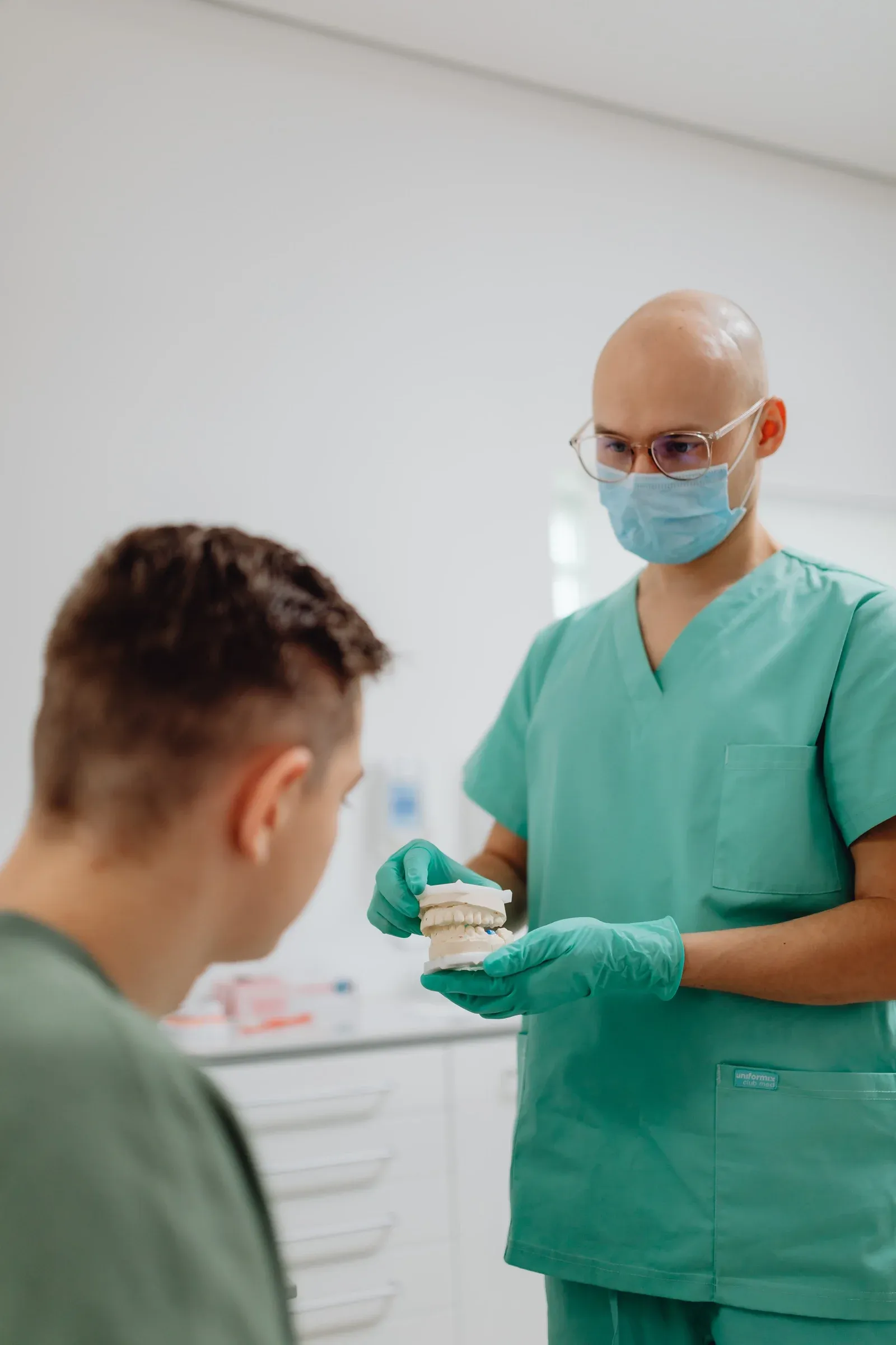 Dentista apresenta um modelo dentário a um homem durante uma conversa na clínica.