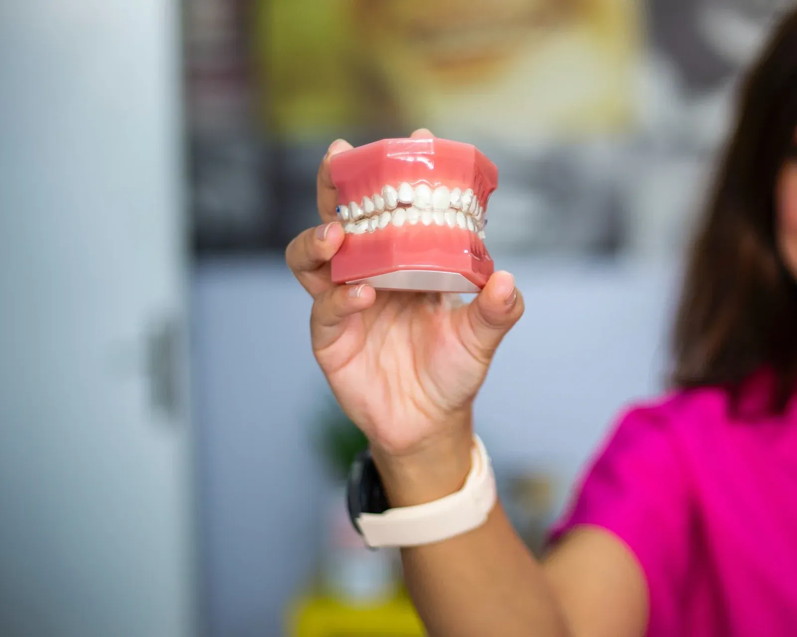 Mão segurando um modelo didático das arcadas dentárias.