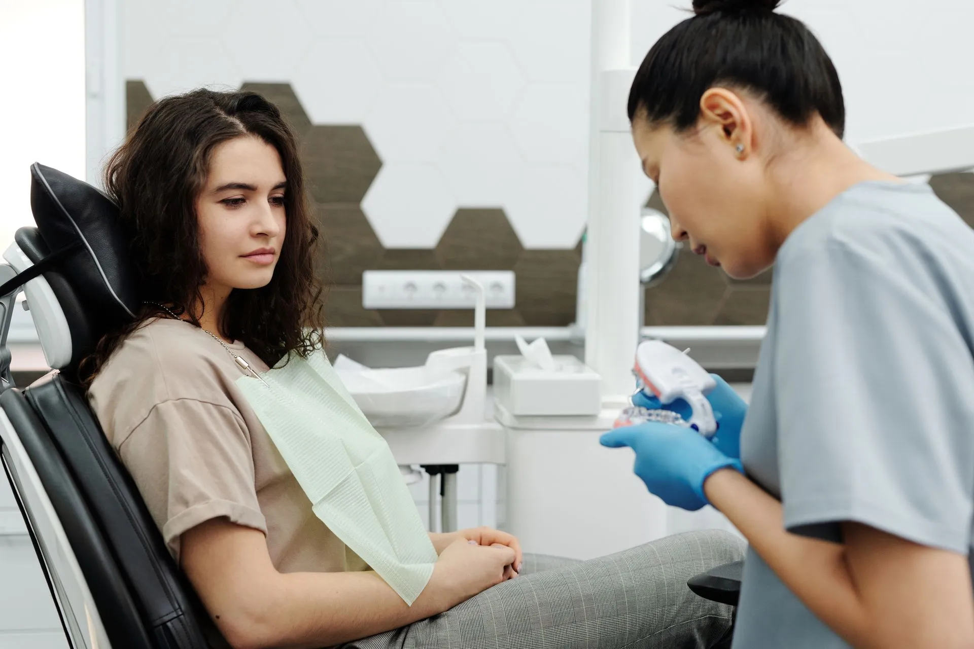 Dentista apresenta um modelo dentário a uma paciente durante uma consulta.