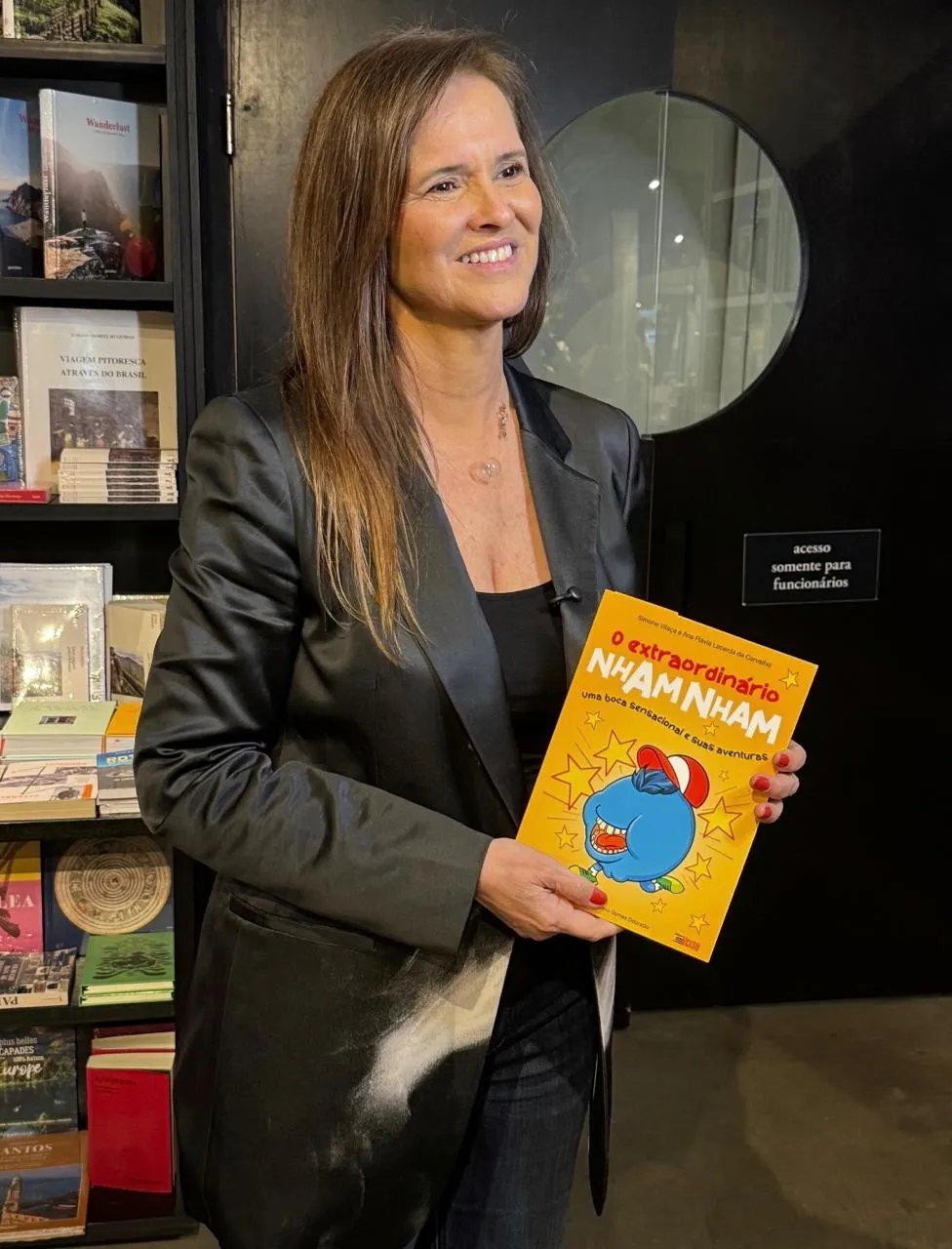 Dra. Simone Carrara segurando o livro infantil O extraordinário Nham Nham.